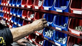 Auswahl an Schrauben in roten und blauben Fächern in einer Werkstatt