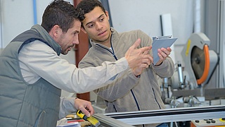 Ausbildungssiuation im Metallbauhandwerk: Ein Ausbilder und ein Lehrling betrachten ein Metallstück