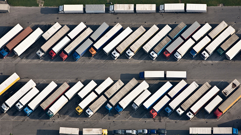 LKW-Parkplatz von oben: Zahlreiche LKW parken schräg zur Fahrbahn dicht nebeneinander.