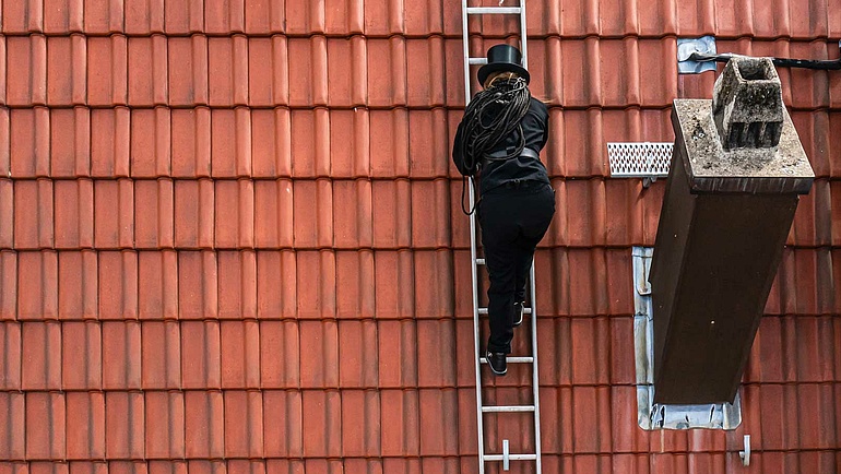 Schornsteinfegerin Julia Bothur auf einem Hausdach.
