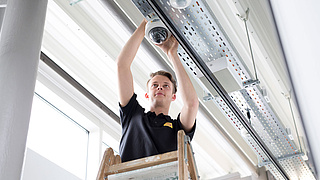 Junger Handwerker installiert eine 360-Grad-Überwachungskamera.