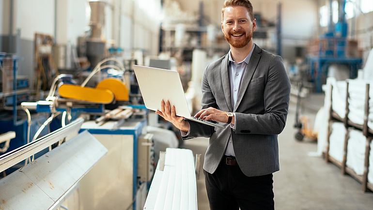 Mann Werkstatt mit Laptop in der Hand