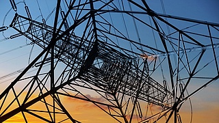 Blick auf einen Stromasten von untern nach oben, bei Sonnenuntergang.